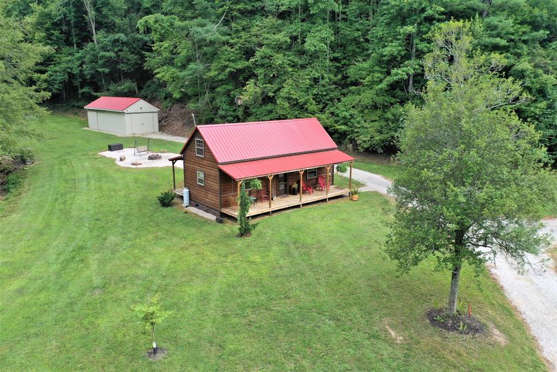 001 low elevation drone shot capturing the cabin, storage building and fire pit area